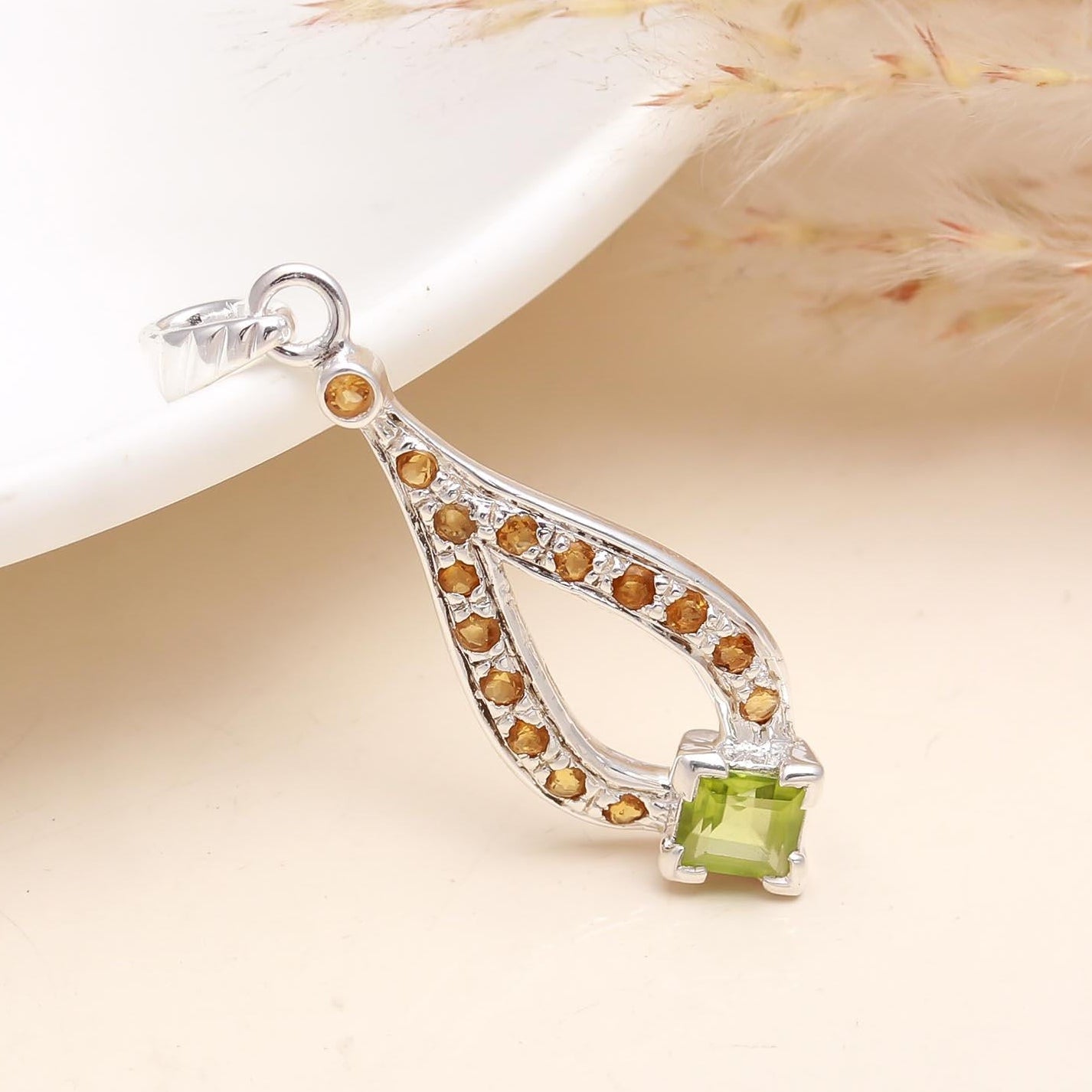 A sterling silver pendant featuring a peridot gemstone set in a classic six-prong setting, with a silver chain, displayed on a faux fur surface.