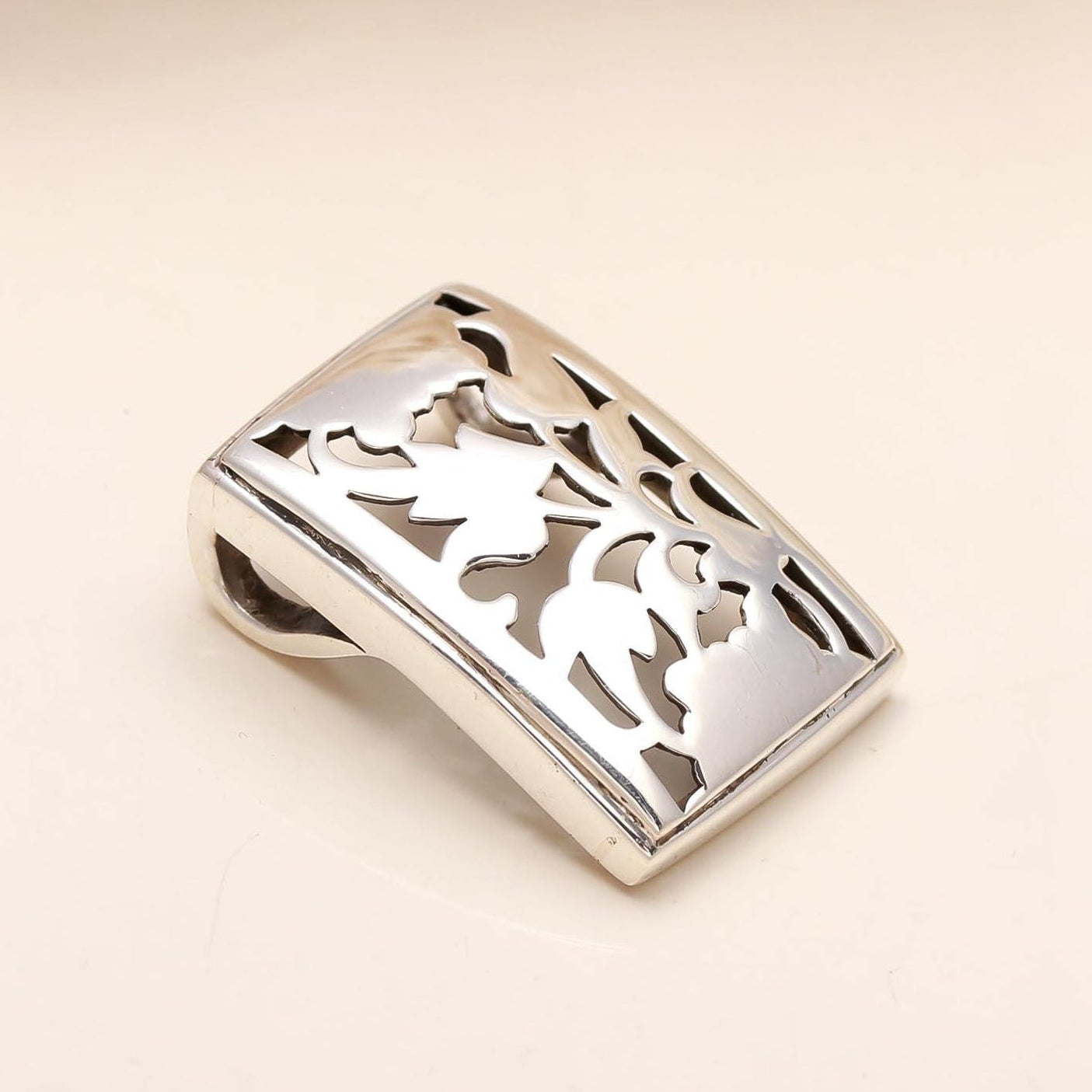 Silver belt buckle with intricate design on a beige background