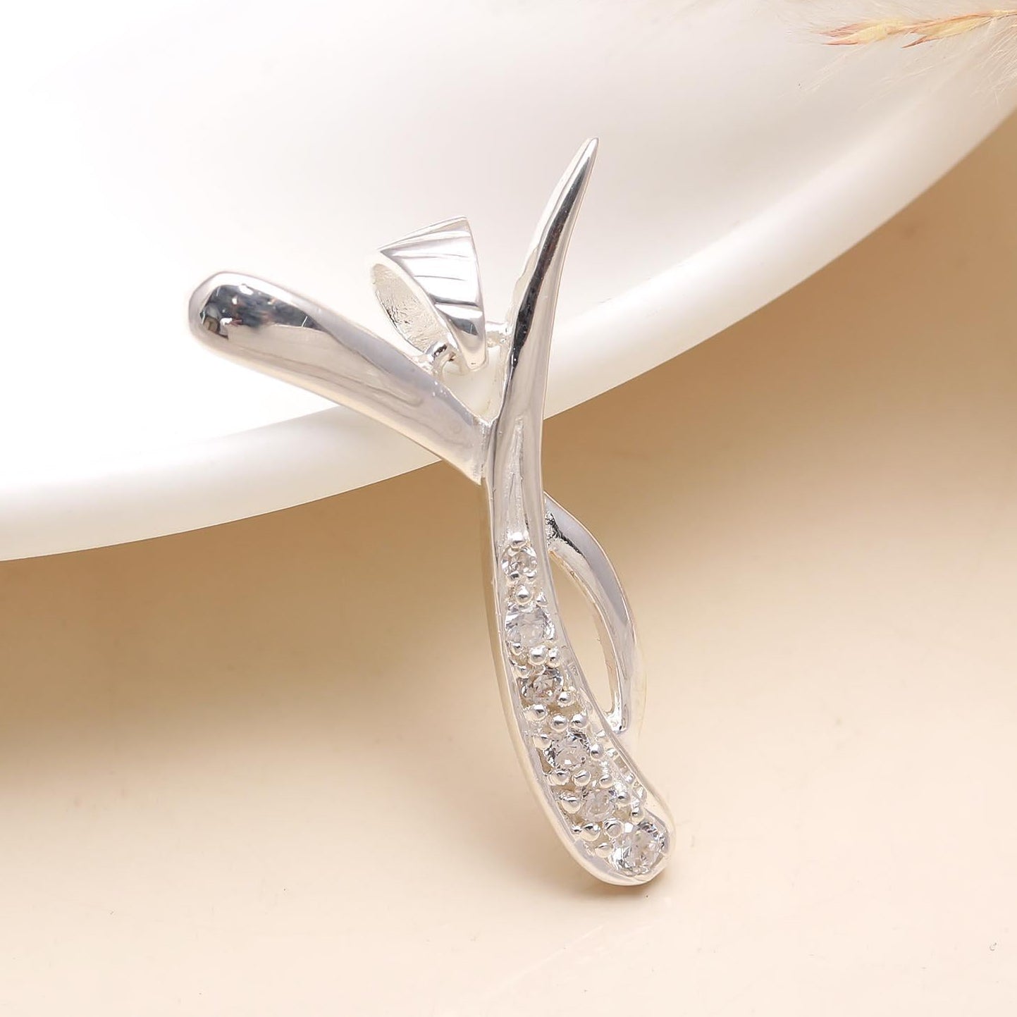 A vintage sterling silver pendant with a cluster design, displayed on a white plate with a blurred background.