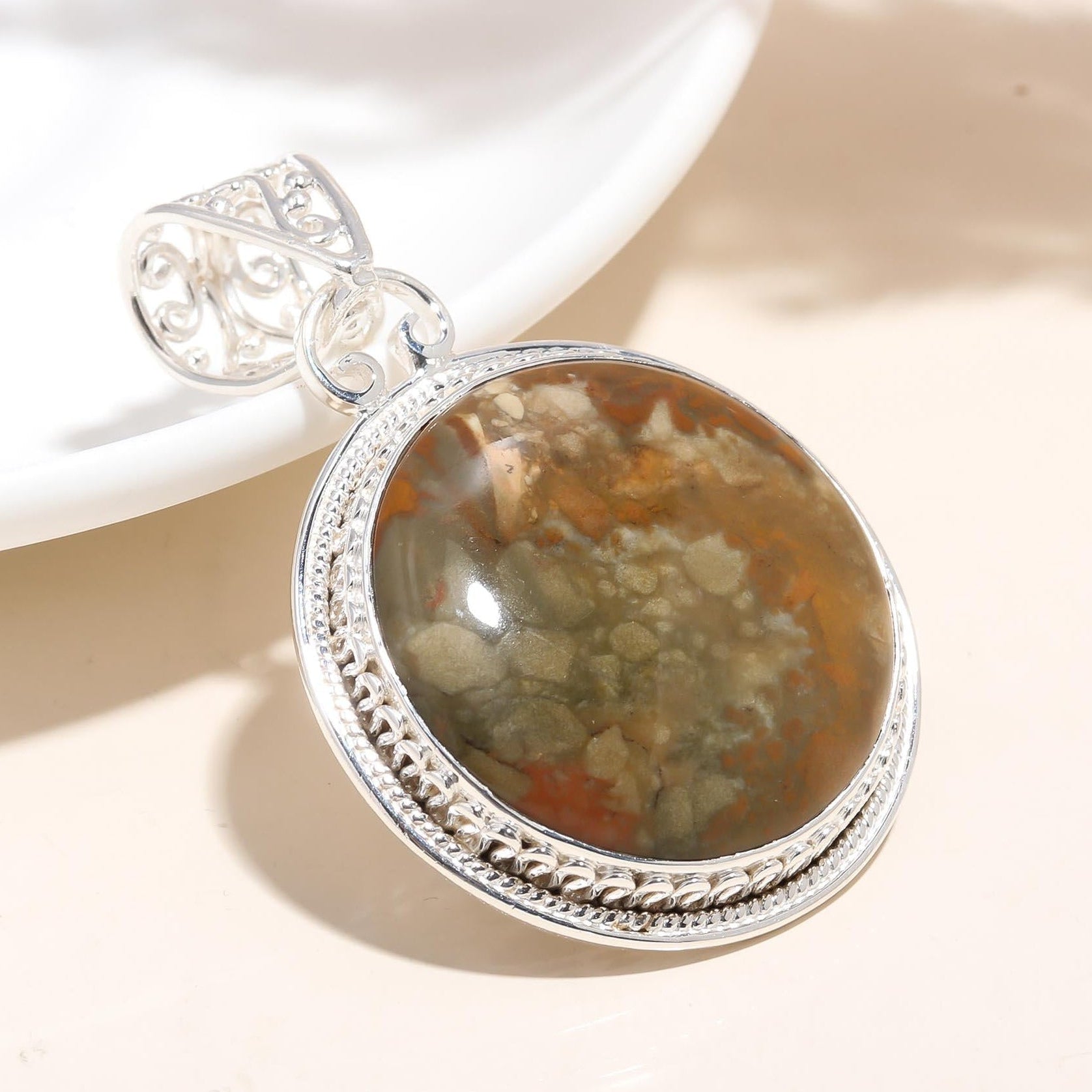 Silver pendant with a natural stone on a light background