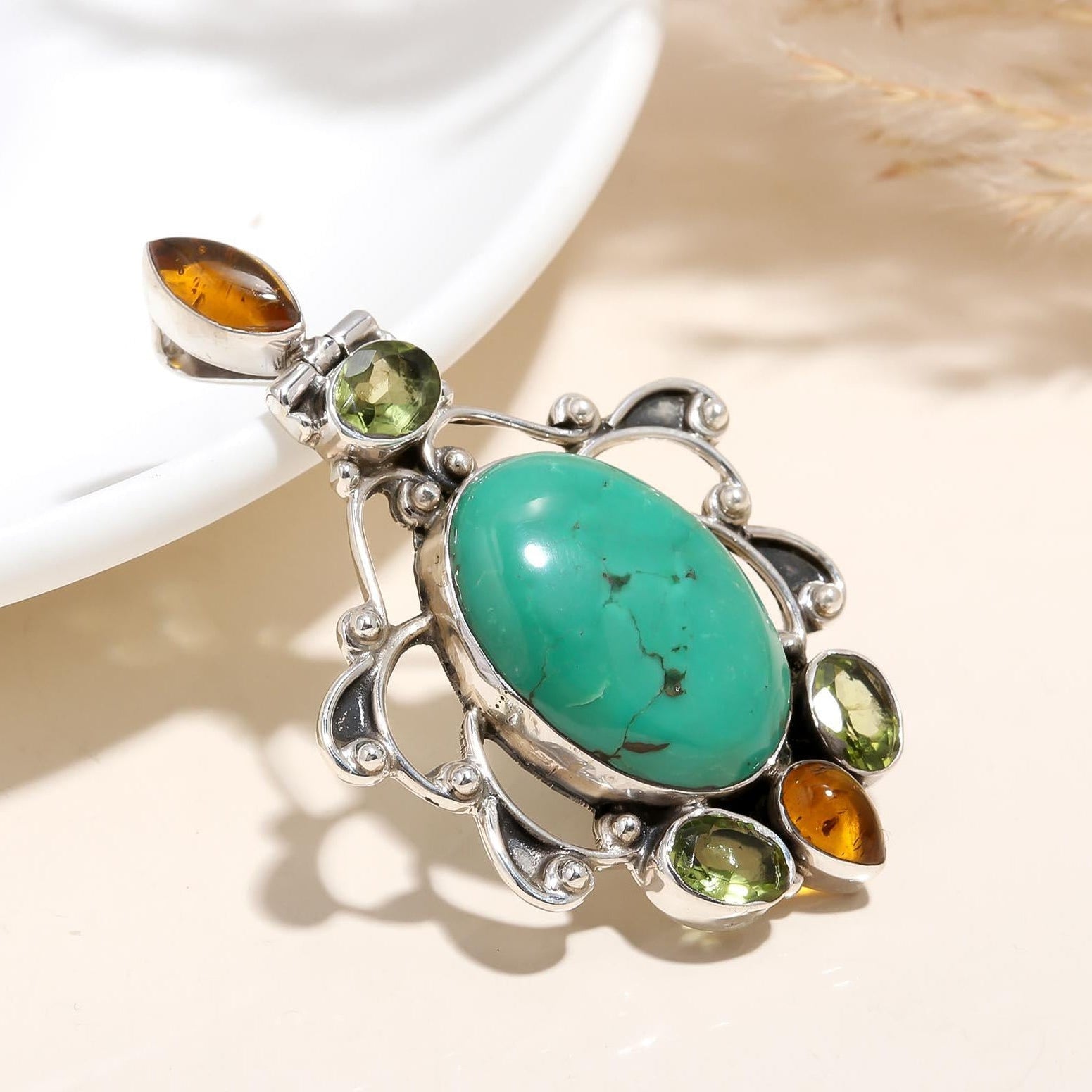 Jewelry pendant with green stone and silver frame on a neutral background