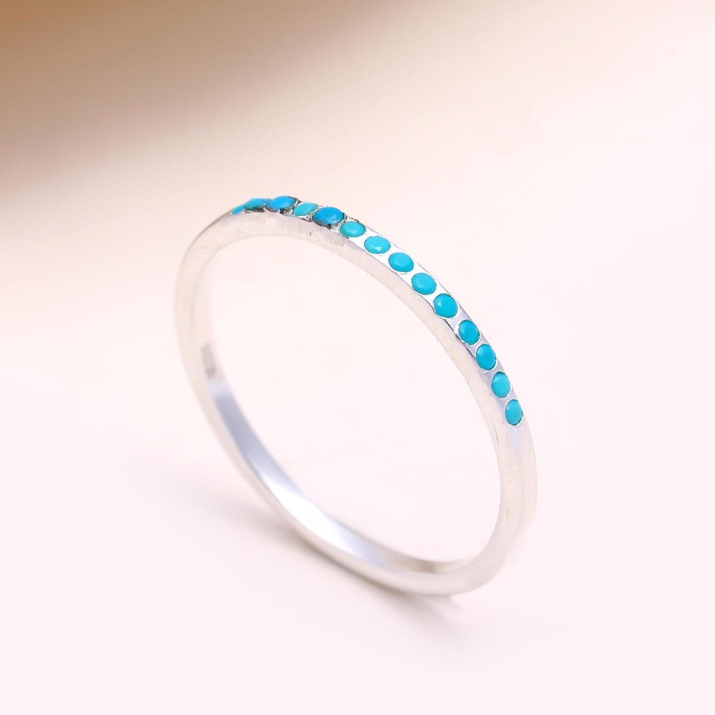 Silver ring with turquoise stones on a beige background