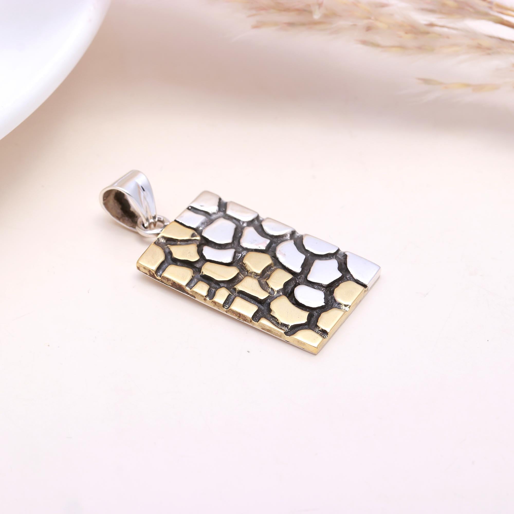 Gold and silver pendant on a light background