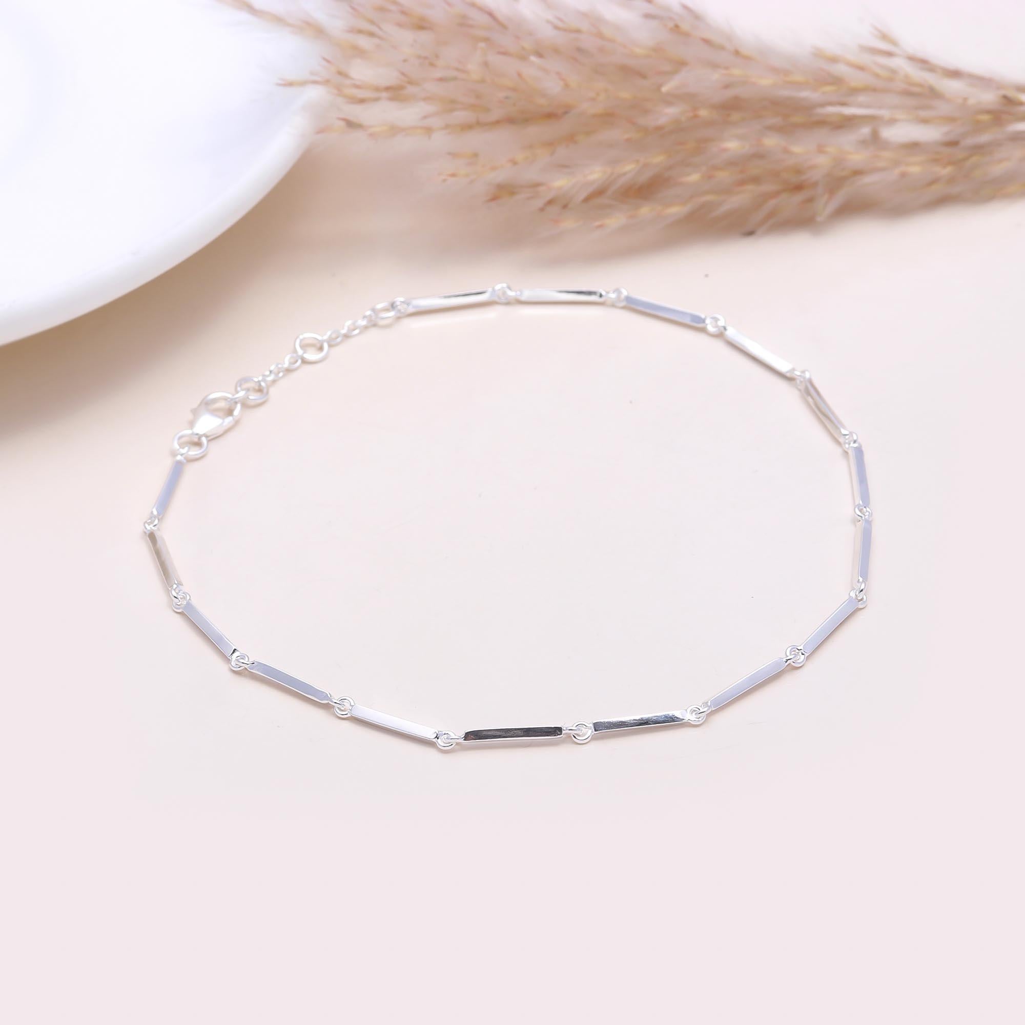 Silver bracelet on a light surface with dried plants in the background