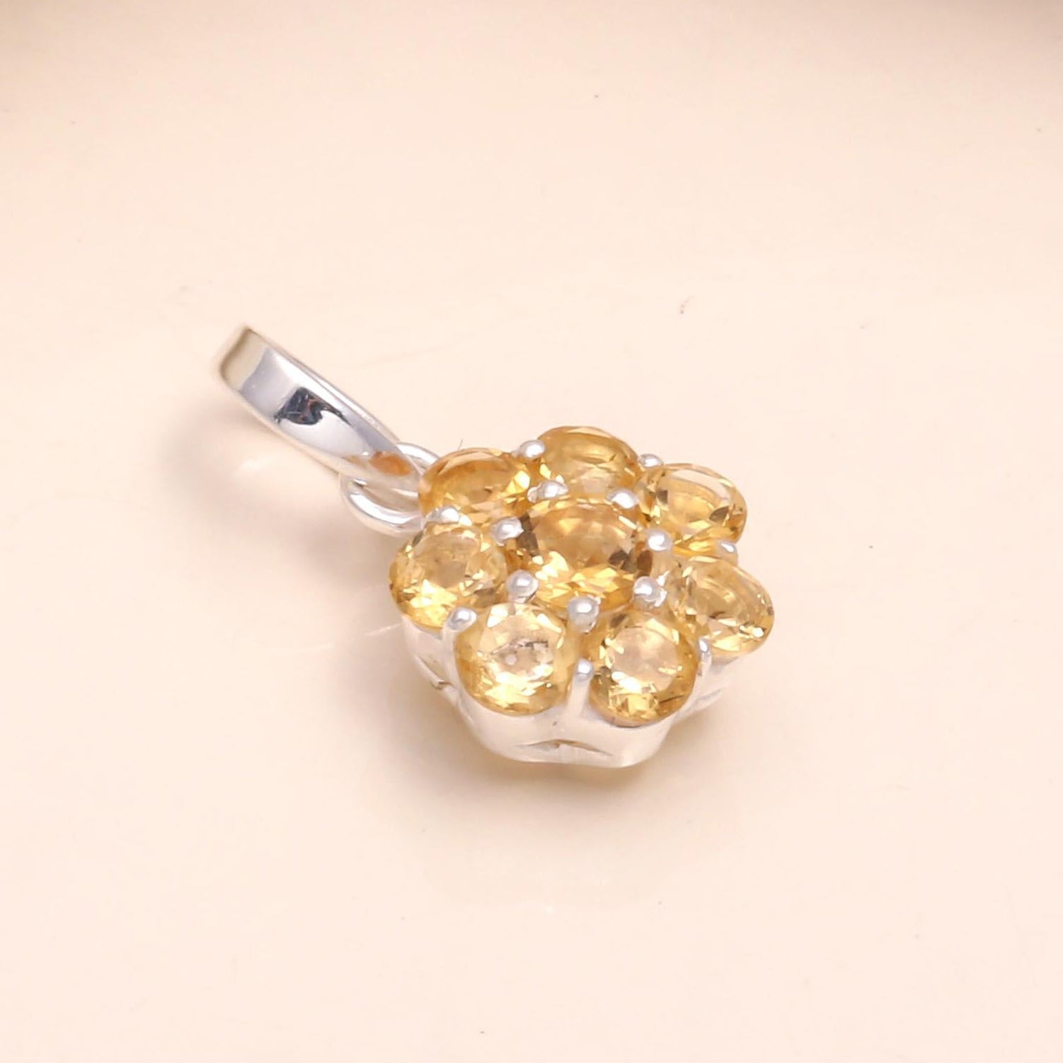 Gold pendant with a silver setting on a beige background