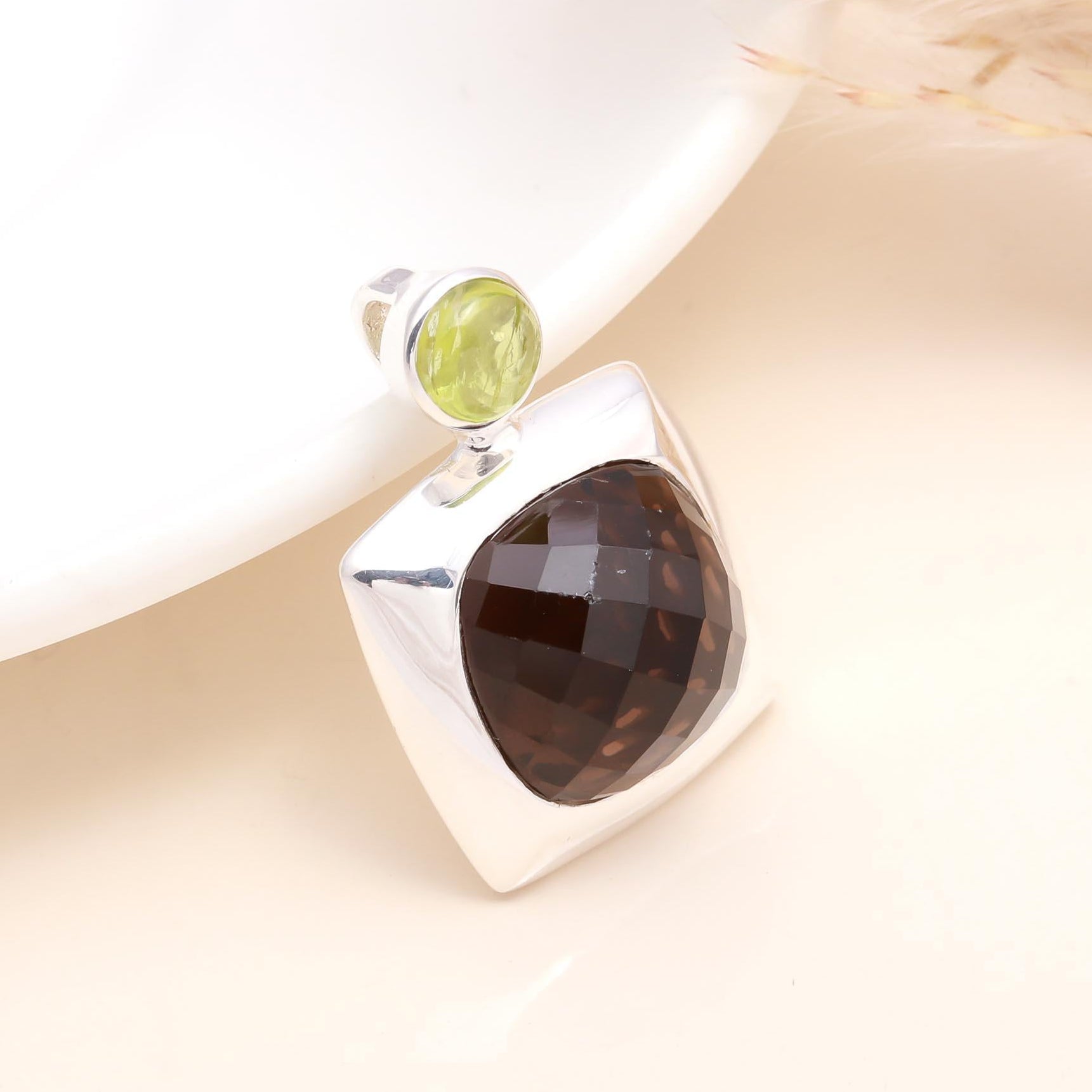 A 925 sterling silver pendant featuring a smoky quartz gemstone with a peridot accent on top, displayed against a light background.