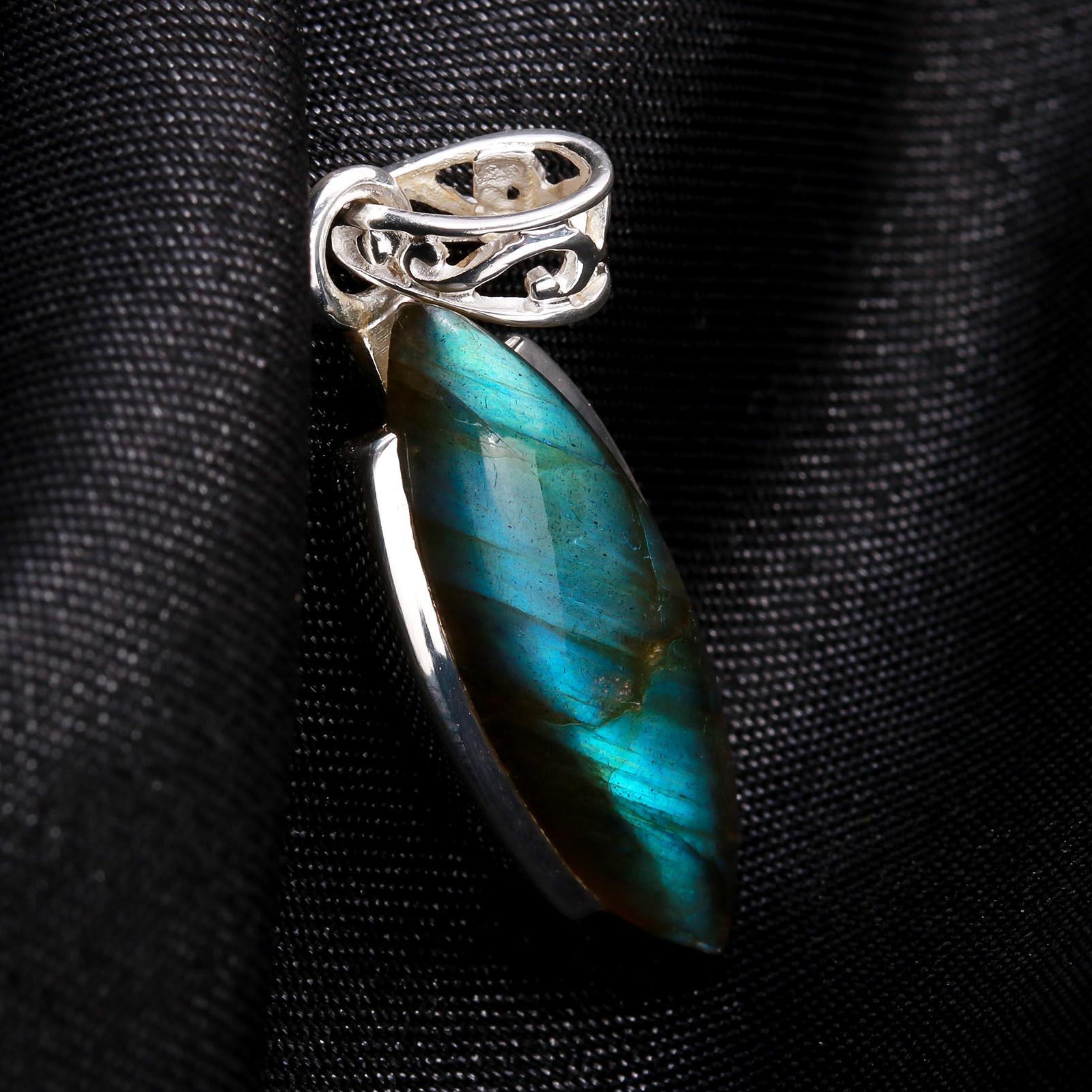 A marquise-cut labradorite gemstone pendant set in a 925 sterling silver artisanal mounting, displayed against a black fabric background.