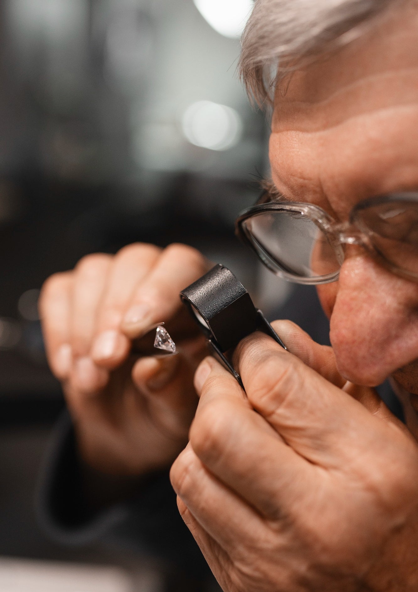 Close-up of a person examining a diamond with a loupe.
