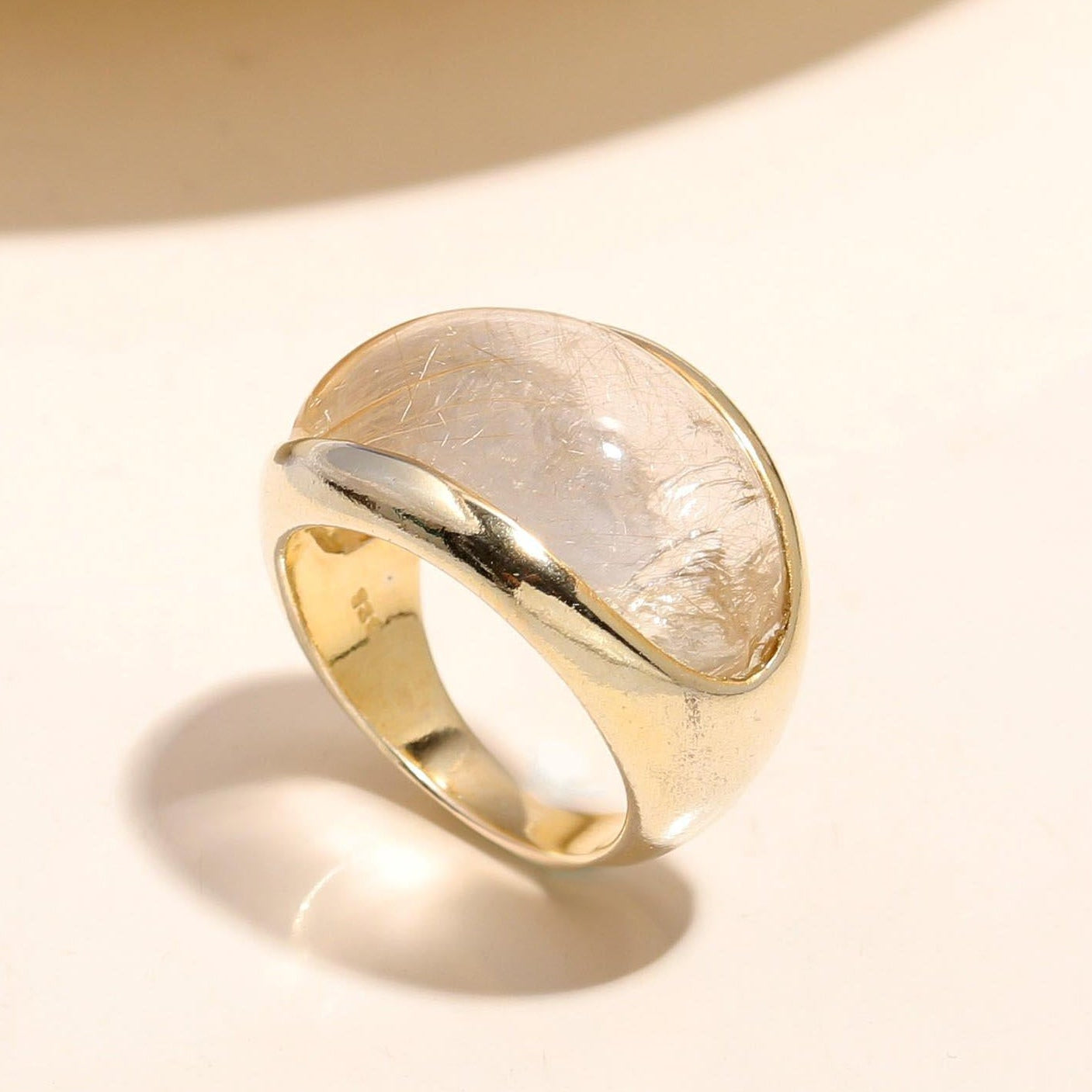 Gold ring with a textured surface on a light beige background