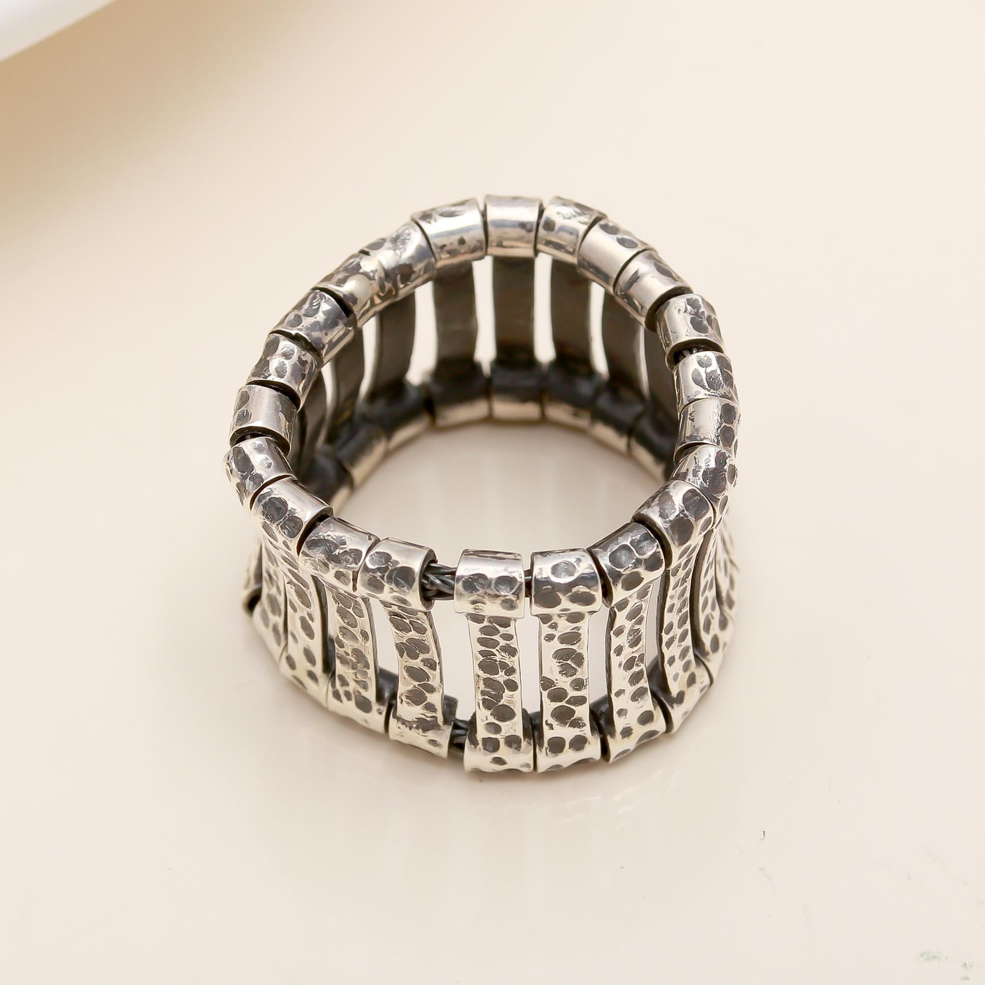 Silver ring with textured design on a beige background