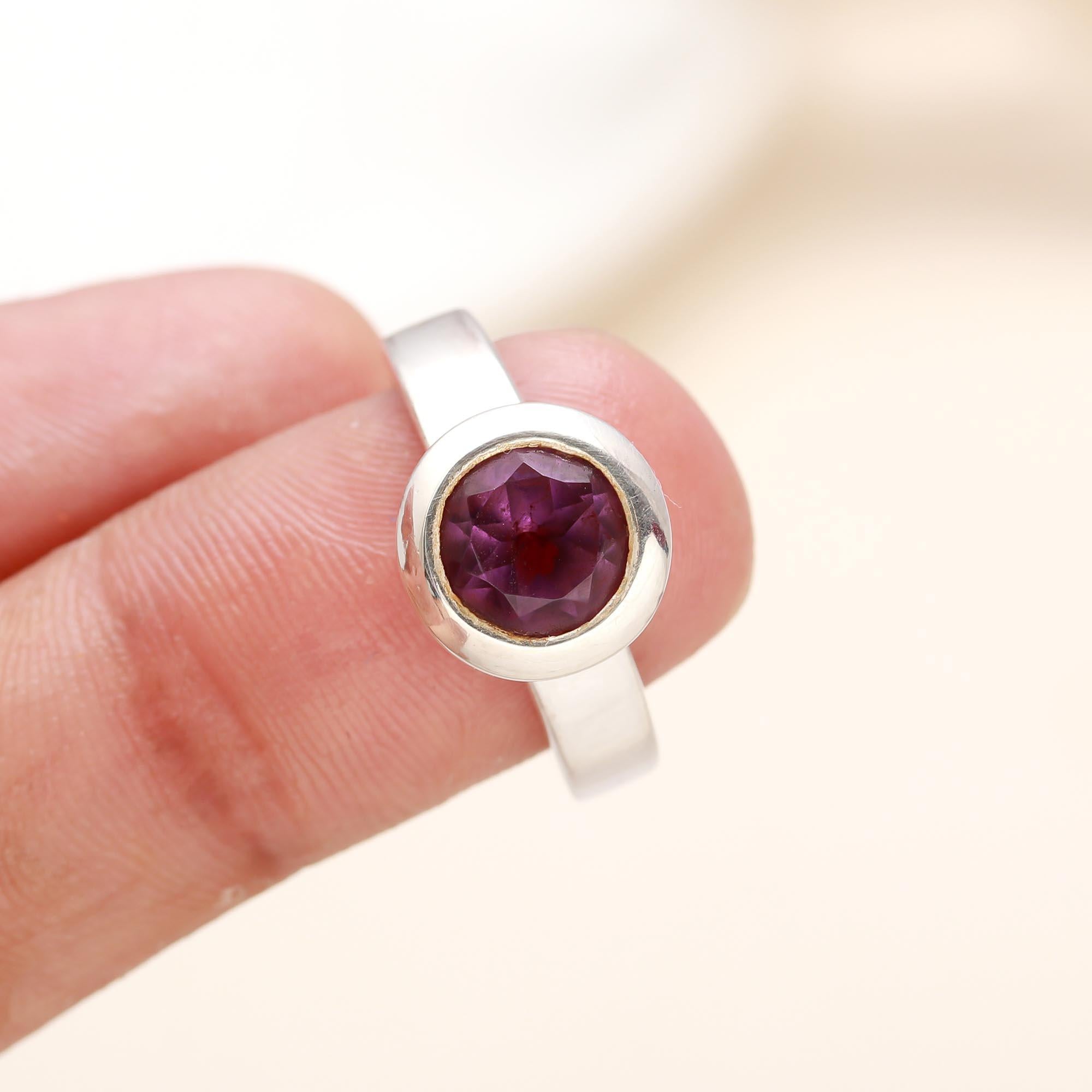 Close-up of round rhodolite garnet in smooth bezel silver setting