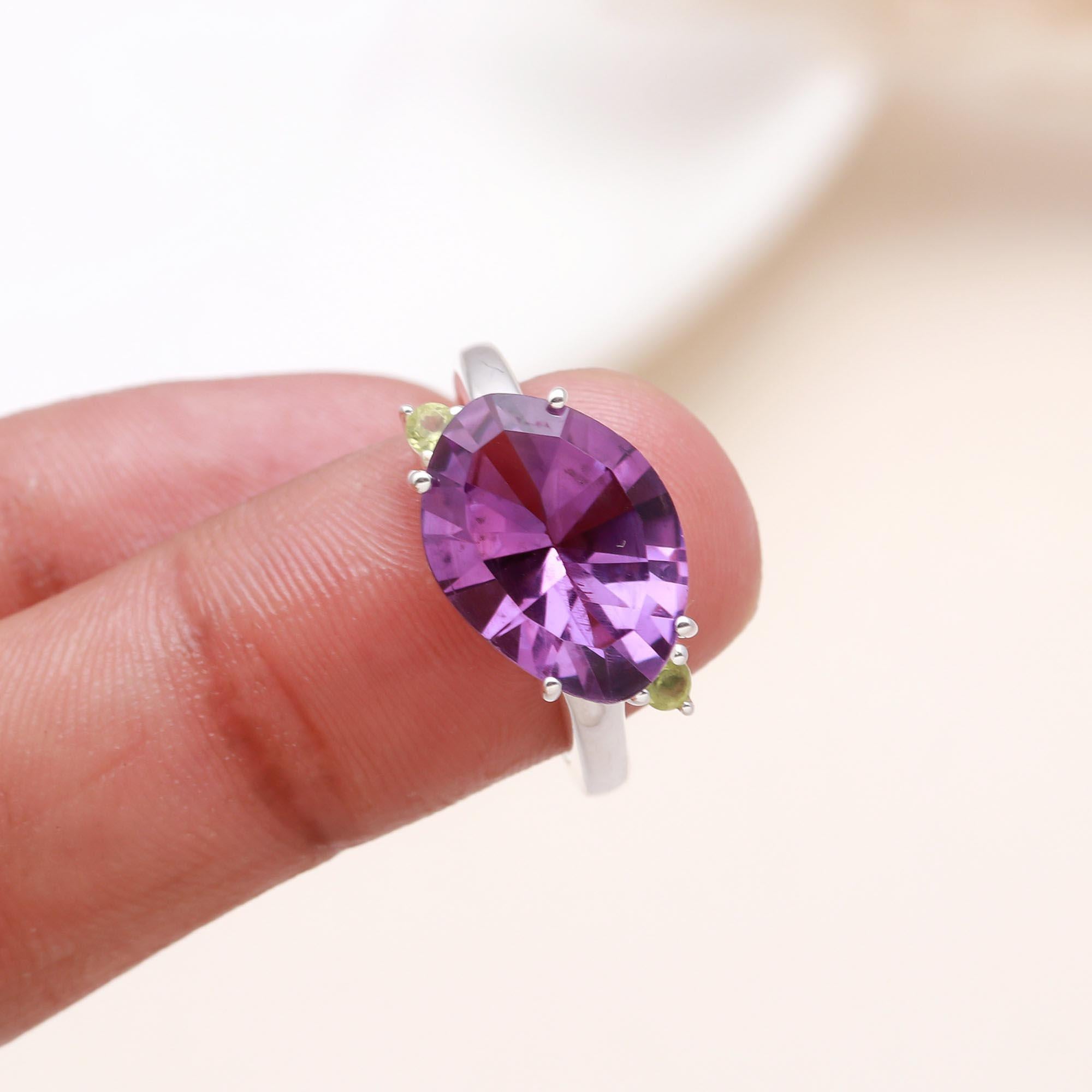 Purple amethyst and green peridot silver ring on finger
