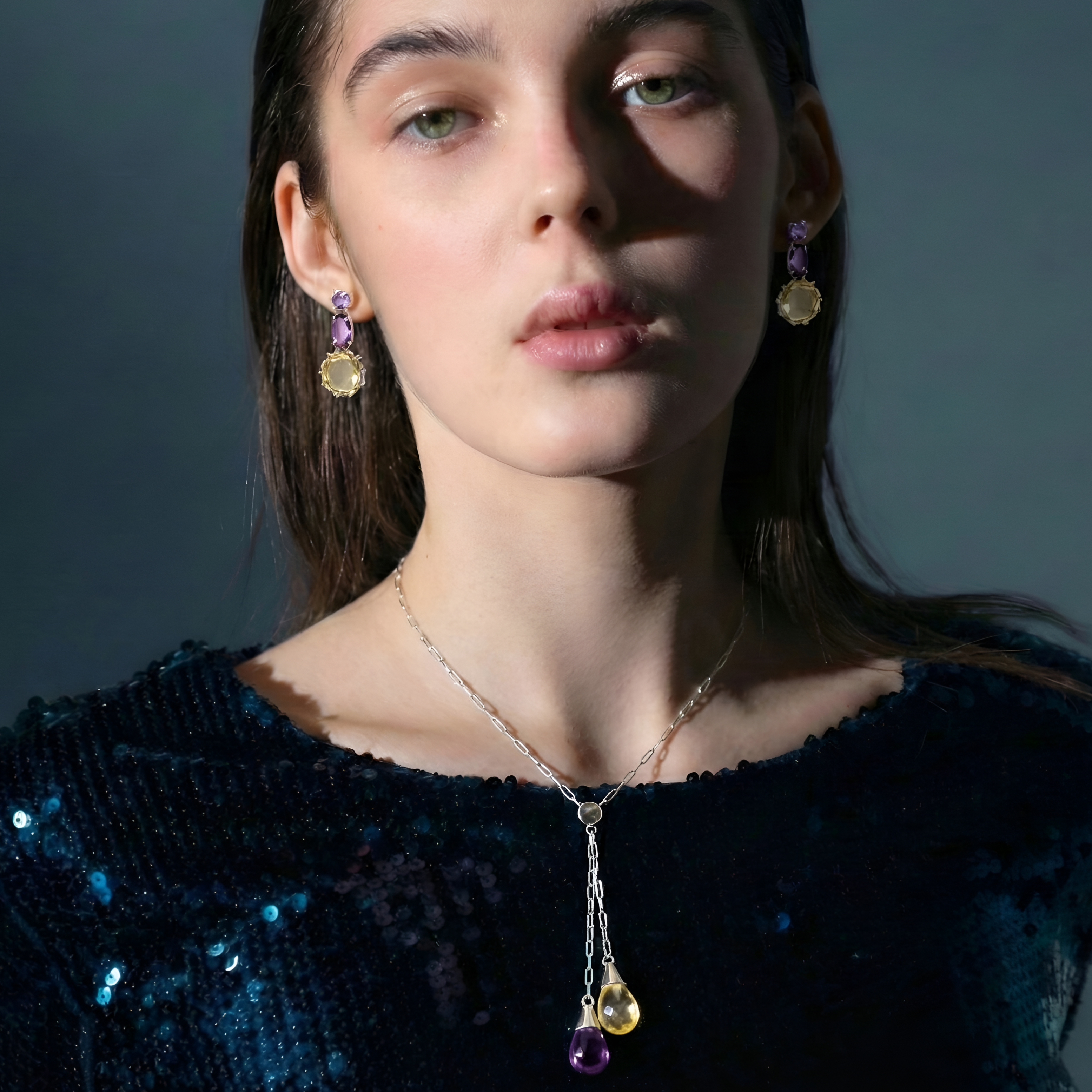 Woman wearing a necklace and earrings against a dark background