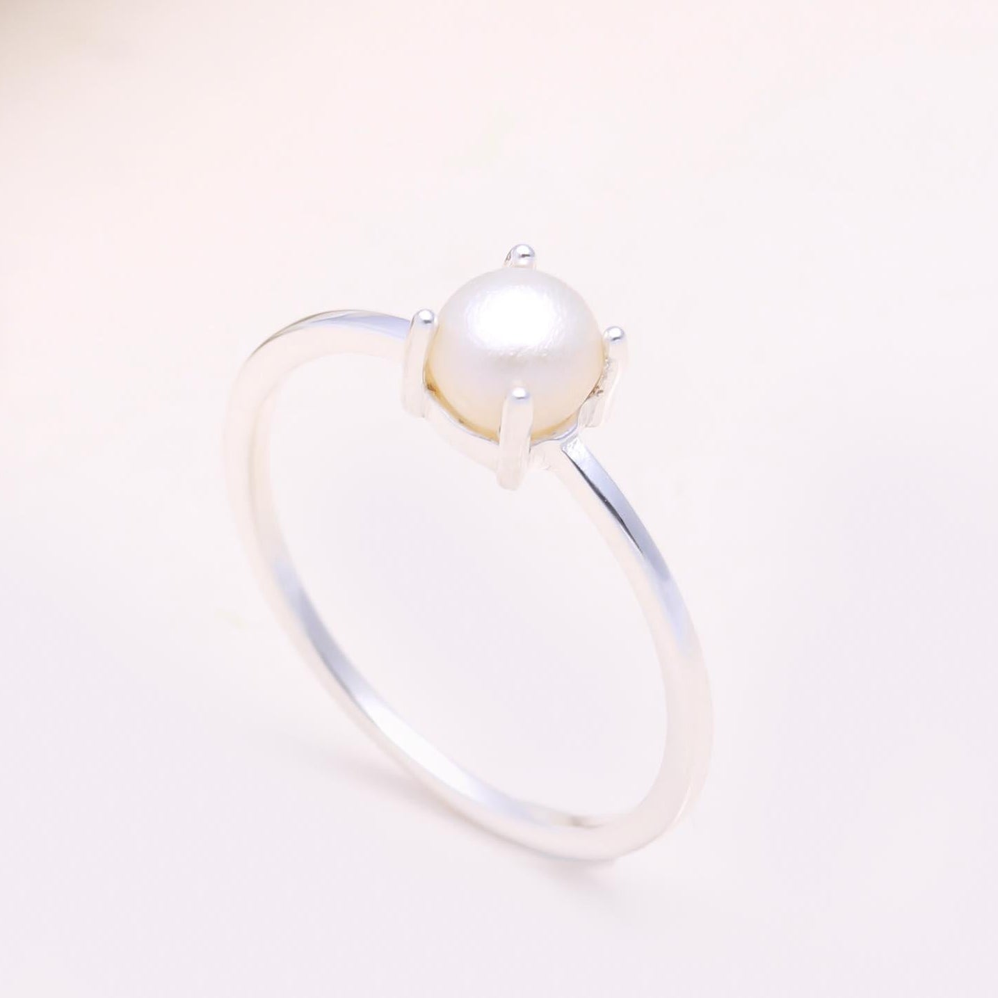 Pearl ring on a light pink background