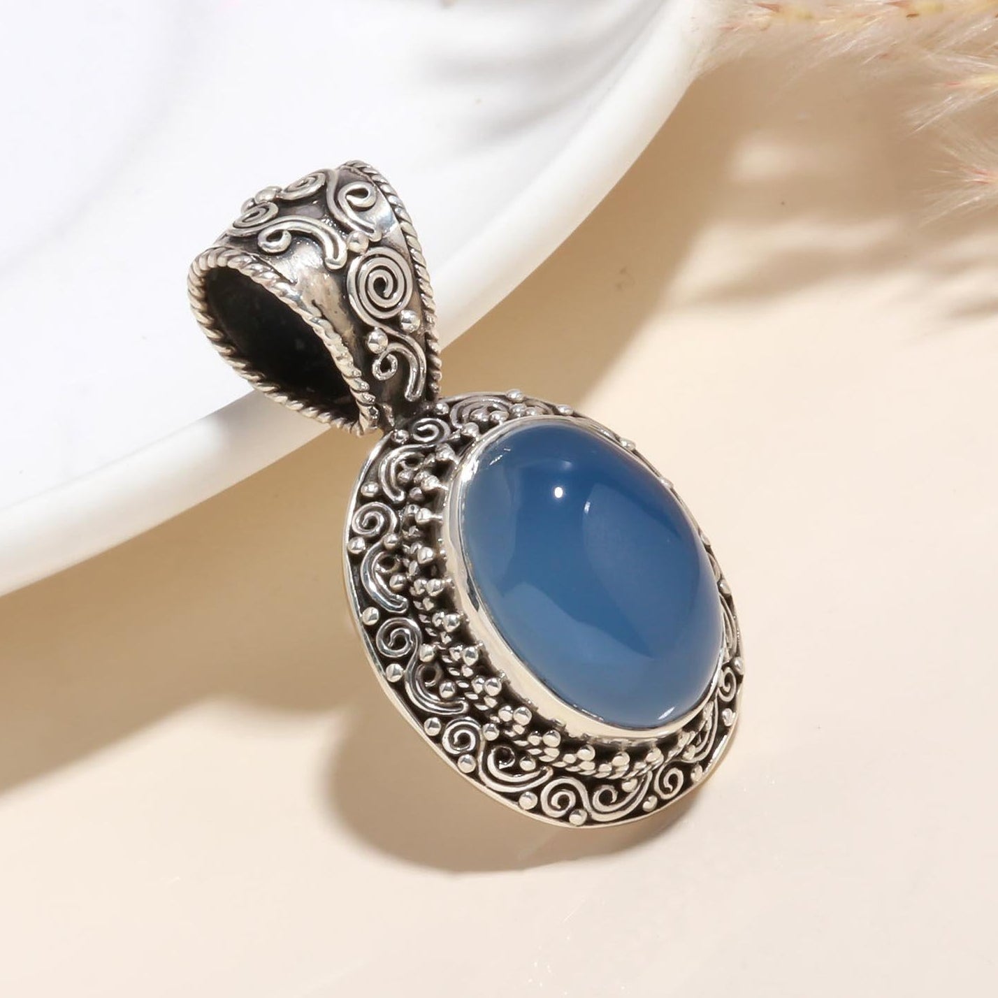 A 925 Sterling Silver Vintage Blue Chalcedony Pendant with intricate silver detailing around the blue gemstone, displayed against a light background.
