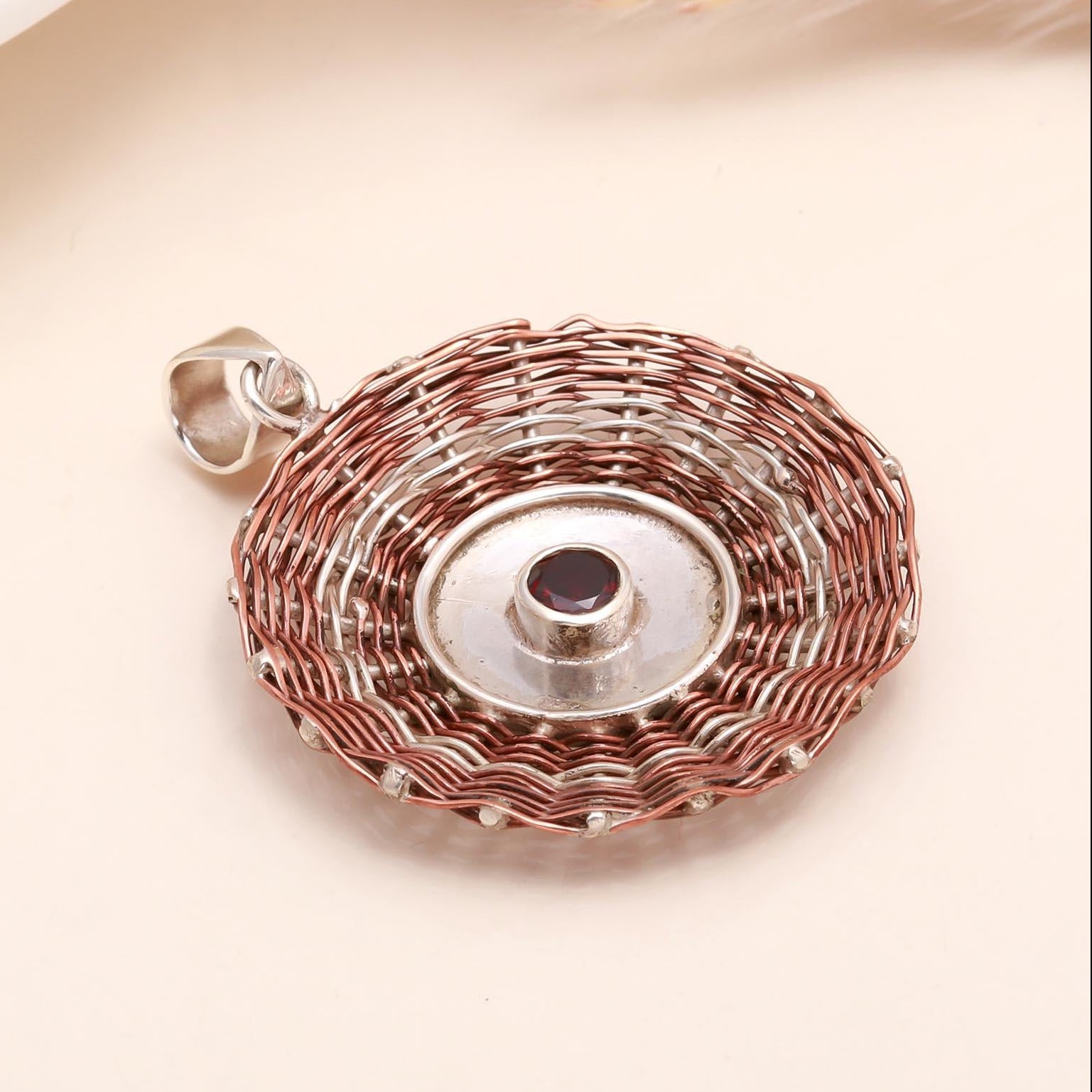 Rose gold and silver pendant on a light pink background
