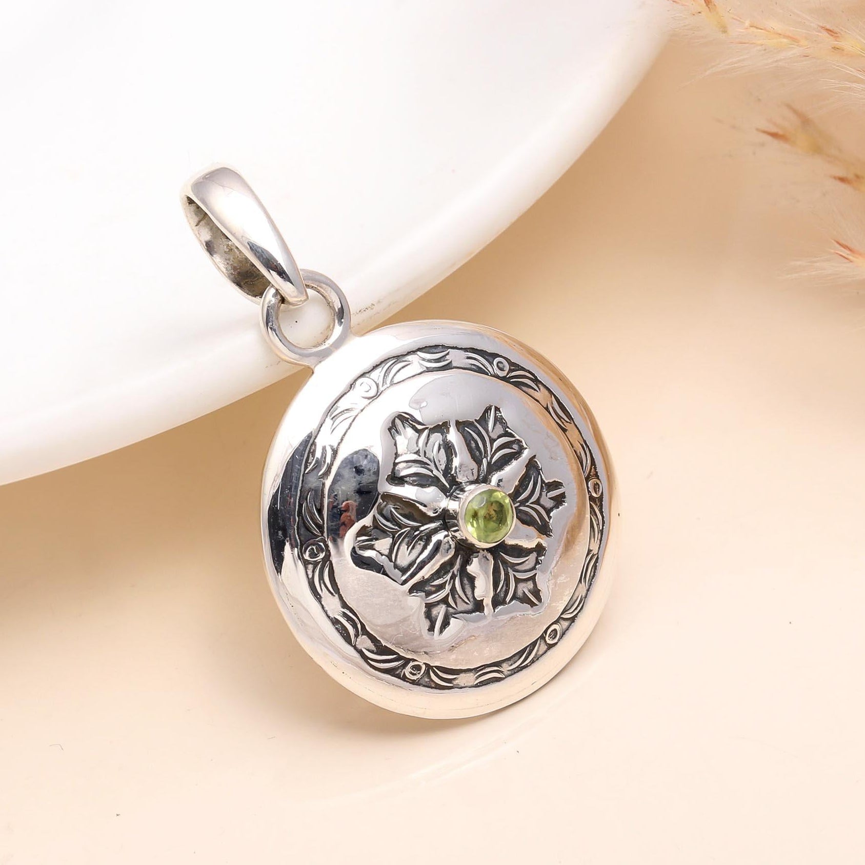 A 925 Sterling Silver pendant with a vintage floral design and a green peridot gemstone in the center, displayed against a neutral background.
