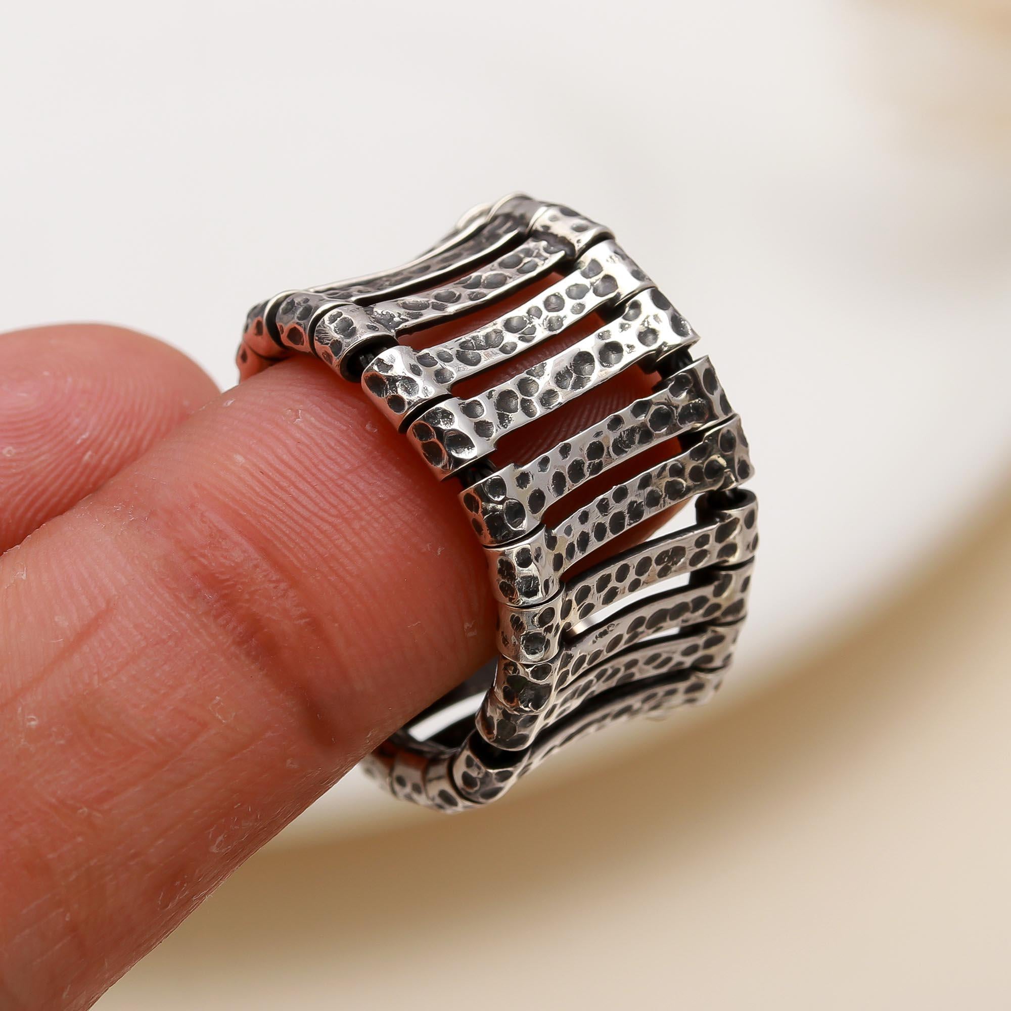Silver textured ring on a finger with a blurred background
