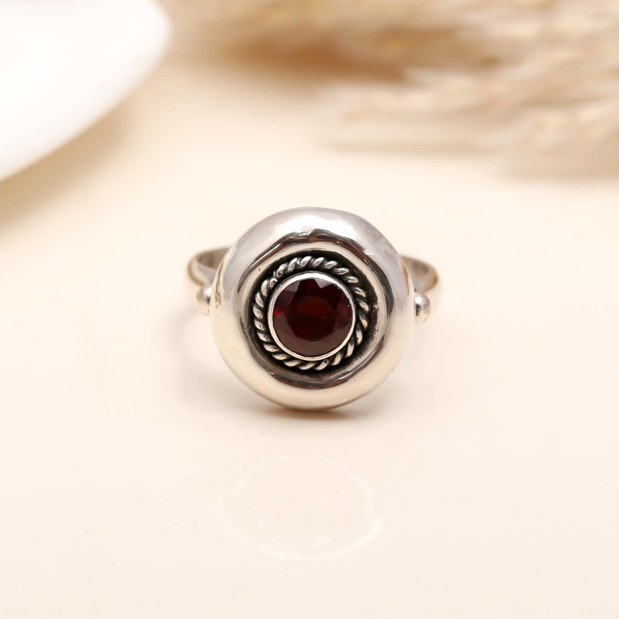 Detailed rope pattern around garnet in silver ring