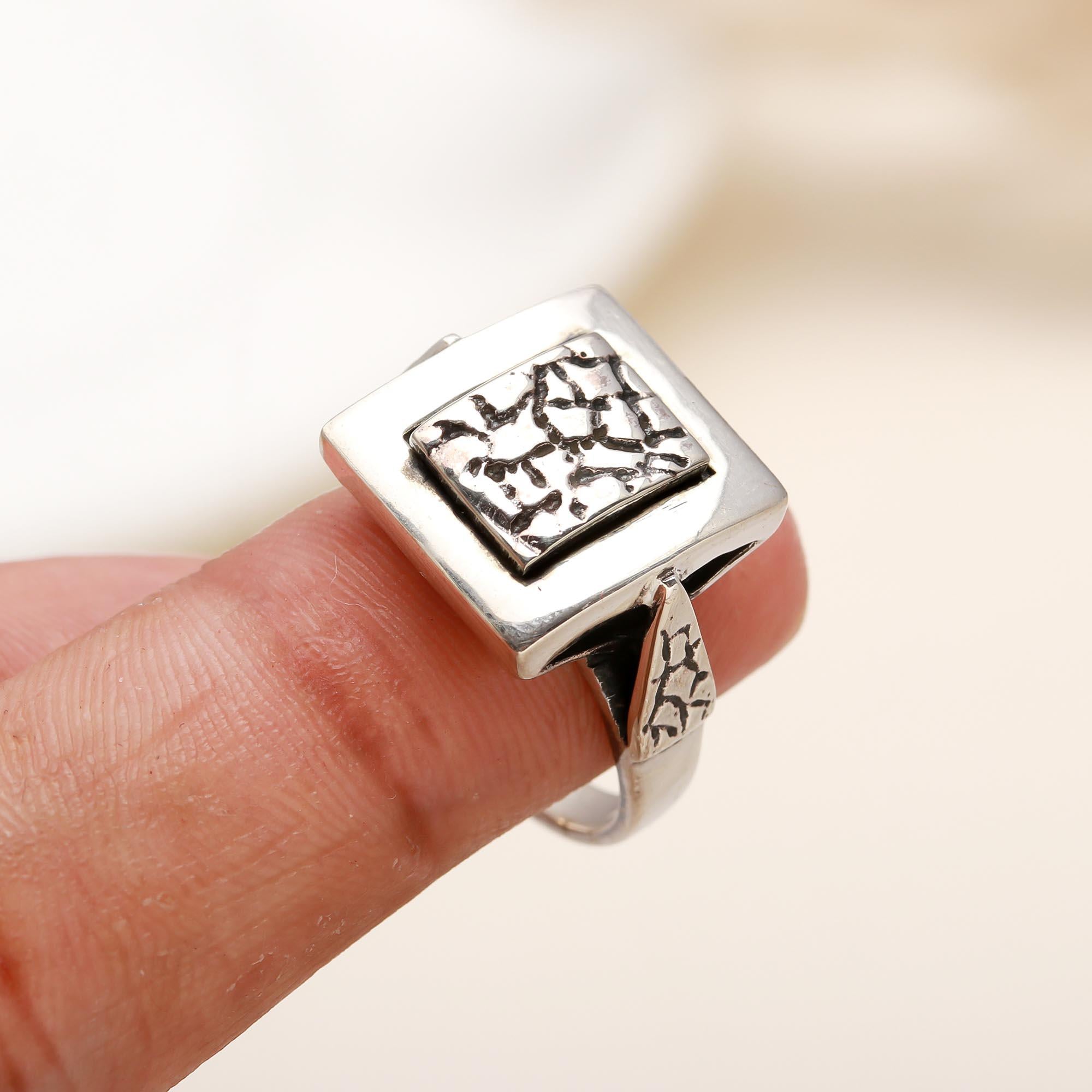 Modern square silver statement ring on finger
